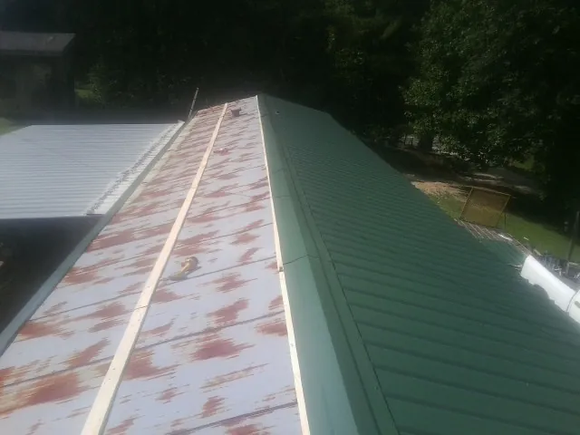 Old rusted panels beside newly installed green metal roofing — Wind Damage Roof Repair by Roofing Brothers in Cascade Locks