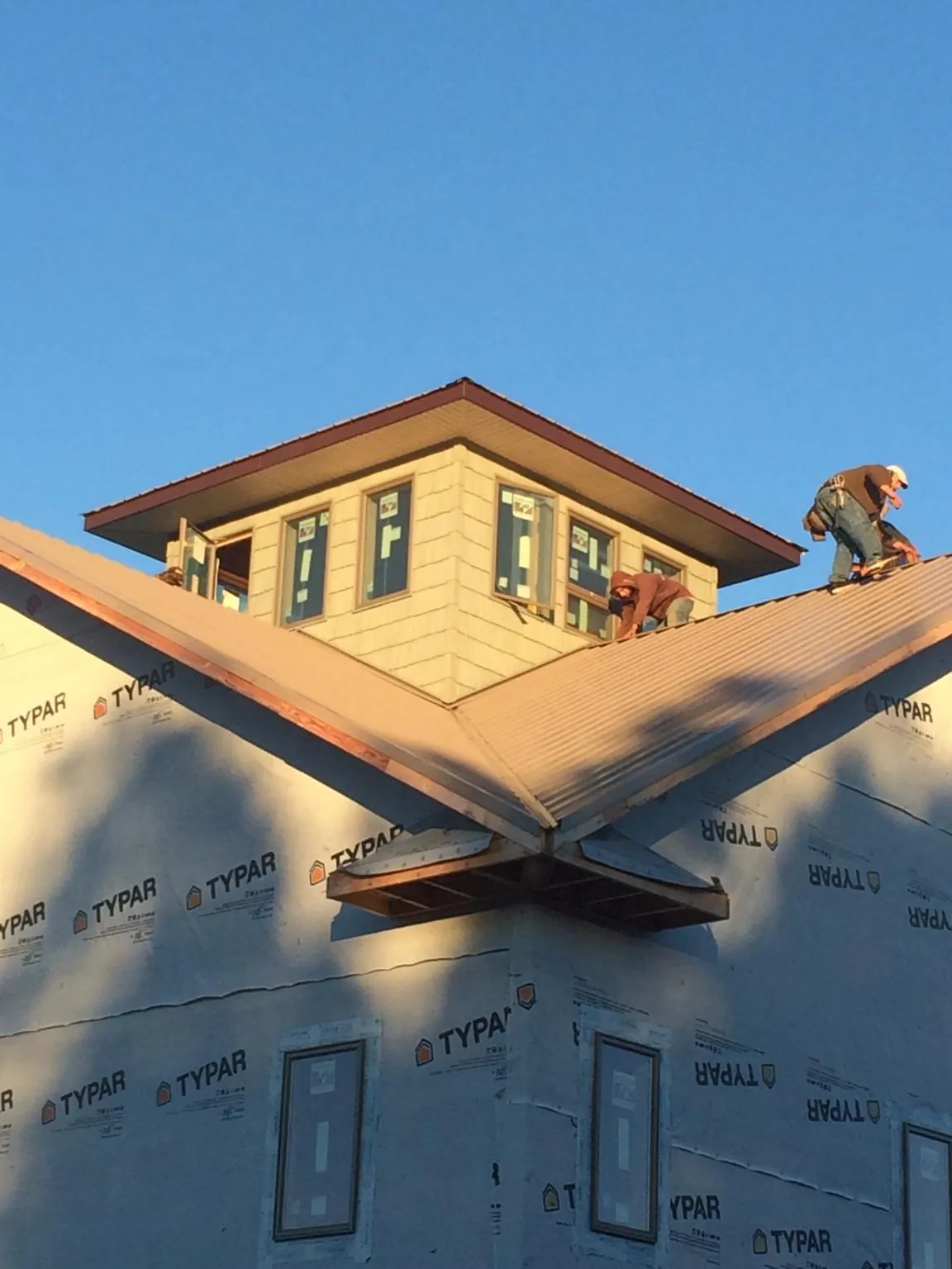 Roofers working around a rooftop cupola on a new metal roof at sunset — Roof Waterproofing in Cascade Locks by Roofing Brothers